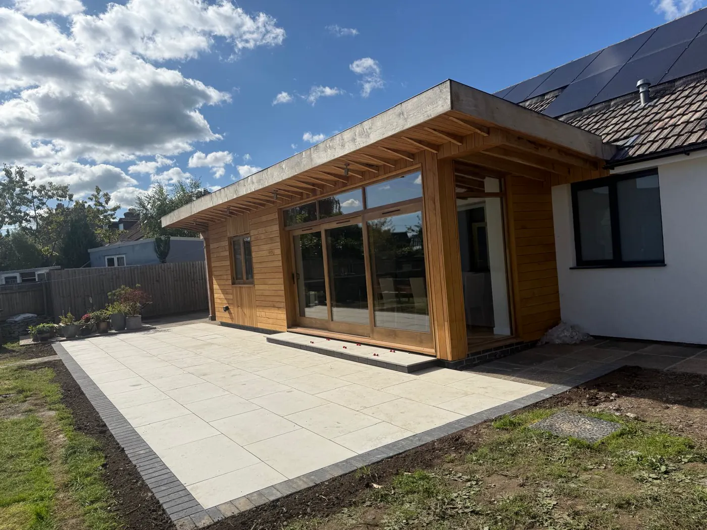 Completed timber-clad home extension opening onto a new patio
